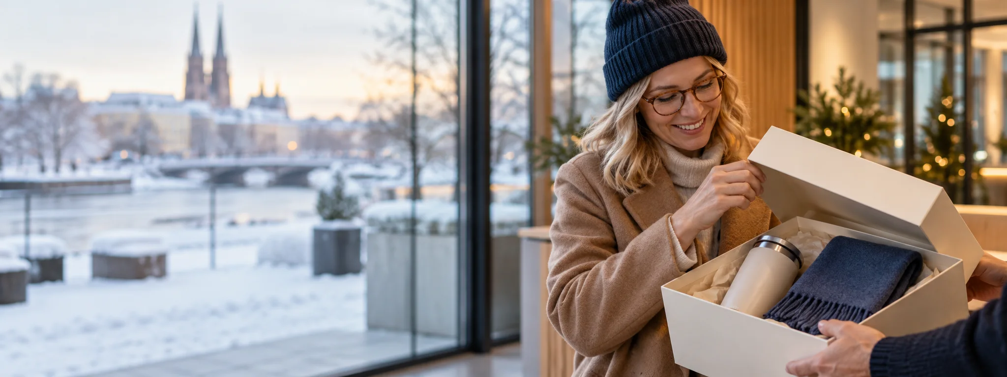 Kvinna öppnar en presentbox med termosmugg och halsduk